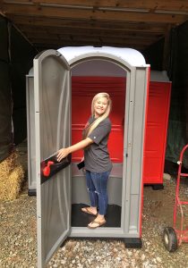 girl stepping out of Portable toilet